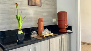 Un comptoir de cuisine avec une plante en pot, une machine à café et un distributeur d’eau.