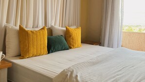 Une chambre d’hôtel avec un grand lit, des rideaux blancs et deux oreillers.