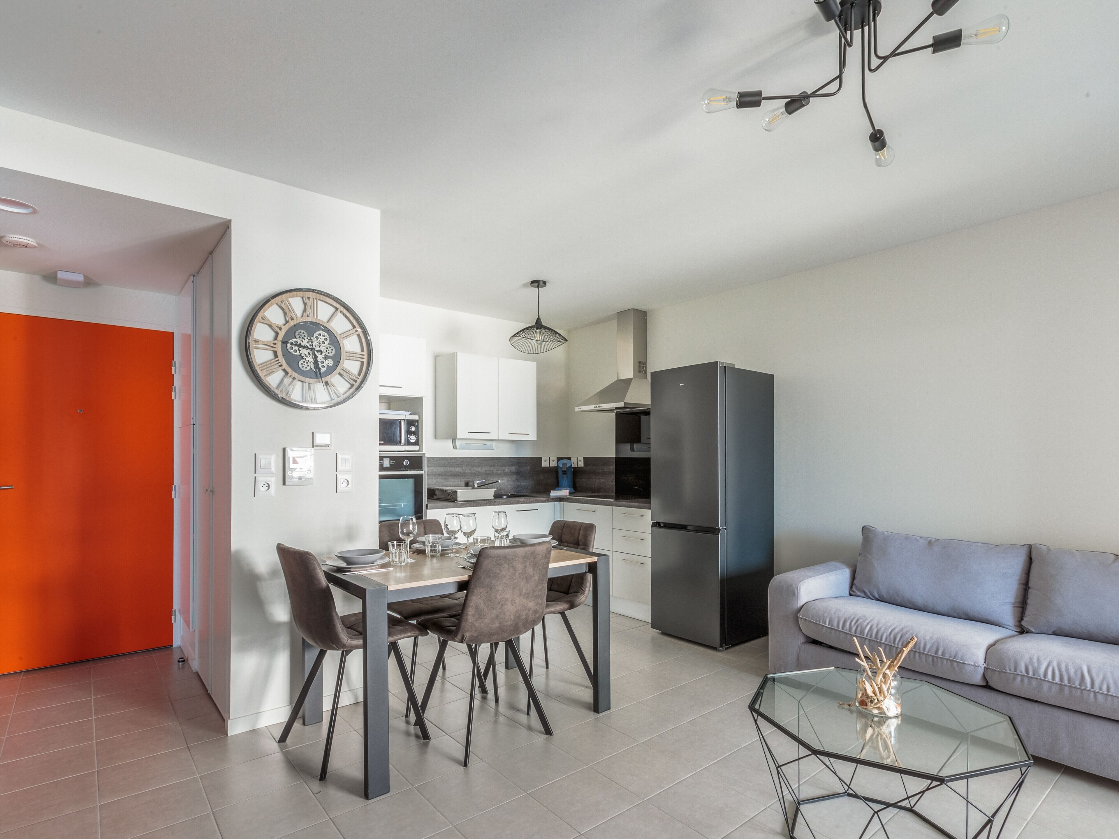 A modern kitchen with a refrigerator, dining table, and chairs.