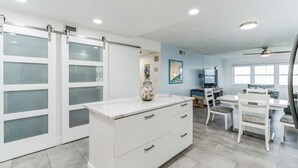 Cocina moderna con muebles blancos, encimera de mármol y un florero con adornos.