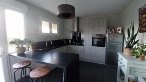 Et moderne køkken med hvide murstensvægge, en sort bordplade, rustfrie stålapparater og træbøtter.