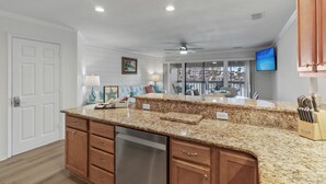A modern kitchen with granite countertops, wooden cabinets, and a built-in dishwasher.