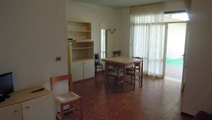 Un espacio habitable compacto con una mesa de comedor, sillas, un televisor y una kitchenette.