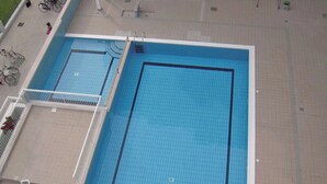 A large outdoor swimming pool with a tiled deck area and a smaller adjacent pool. - Cozy Studio With Pool in Caorle (Caorle)