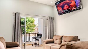A living room with a sofa set, a television mounted on the wall, and a view of the outdoors through a glass door. - Cozy 2-bedroom apartment in charming Tequila with WiFi, AC (Tequila)