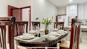 Un coin repas avec une table ronde dressée pour quatre personnes, entourée de chaises en bois.