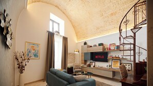 A living room with a sofa, a TV, a staircase, and a bookshelf. - Ex Monastero in Centro Storico a Bitetto, 3 Bedrooms, Free Wi-Fi. (Bitetto)