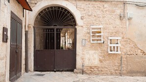 A stone building with a large arched entrance, a metal gate, and a small window with a shelf. - Ex Monastero in Centro Storico a Bitetto, 3 Bedrooms, Free Wi-Fi. (Bitetto)