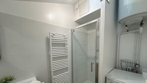 Un bany modern amb una dutxa envidriada, rentamàquina integrada i una barra de tovalloles.
