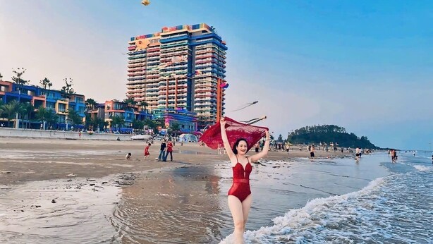 A beach with a high-rise building in the background. - Hotel Sea View (Hoang Tien)