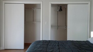 Ein Schlafzimmer mit einem Bett, zwei Schränken mit Regalen und einer Tür.