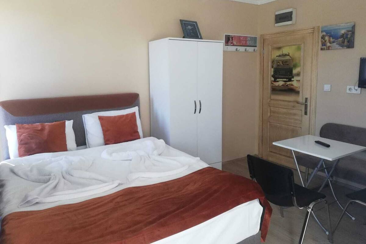 Una habitación de hotel con cama, armario, escritorio y una silla.