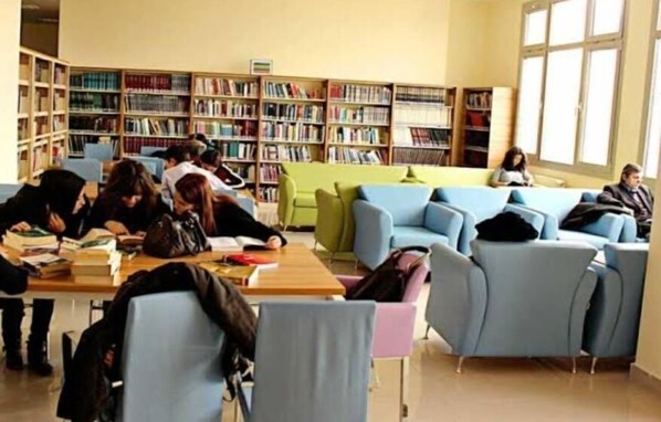 Una biblioteca con varias zonas de estar, estanterías y un ventanal grande.
