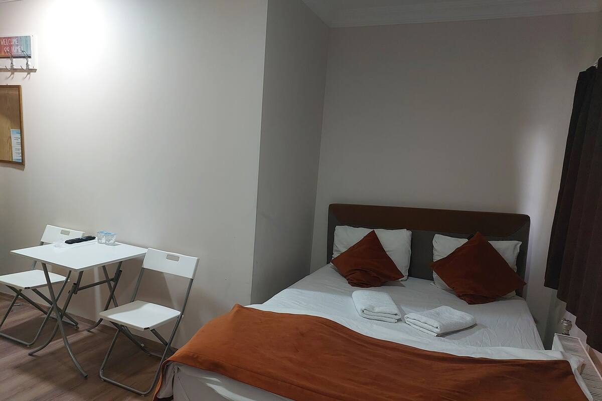 Habitación de hotel con cama, una mesita, dos sillas y un cartel en la pared.