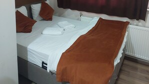Ein Einzelbett mit brauner Decke, weißen Kissen und einer weißen Daunendecke.
