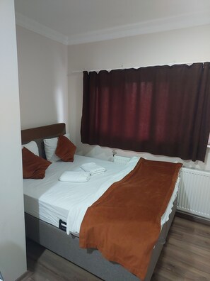 Una cama individual con una manta marrón, almohadas blancas y un edredón blanco.