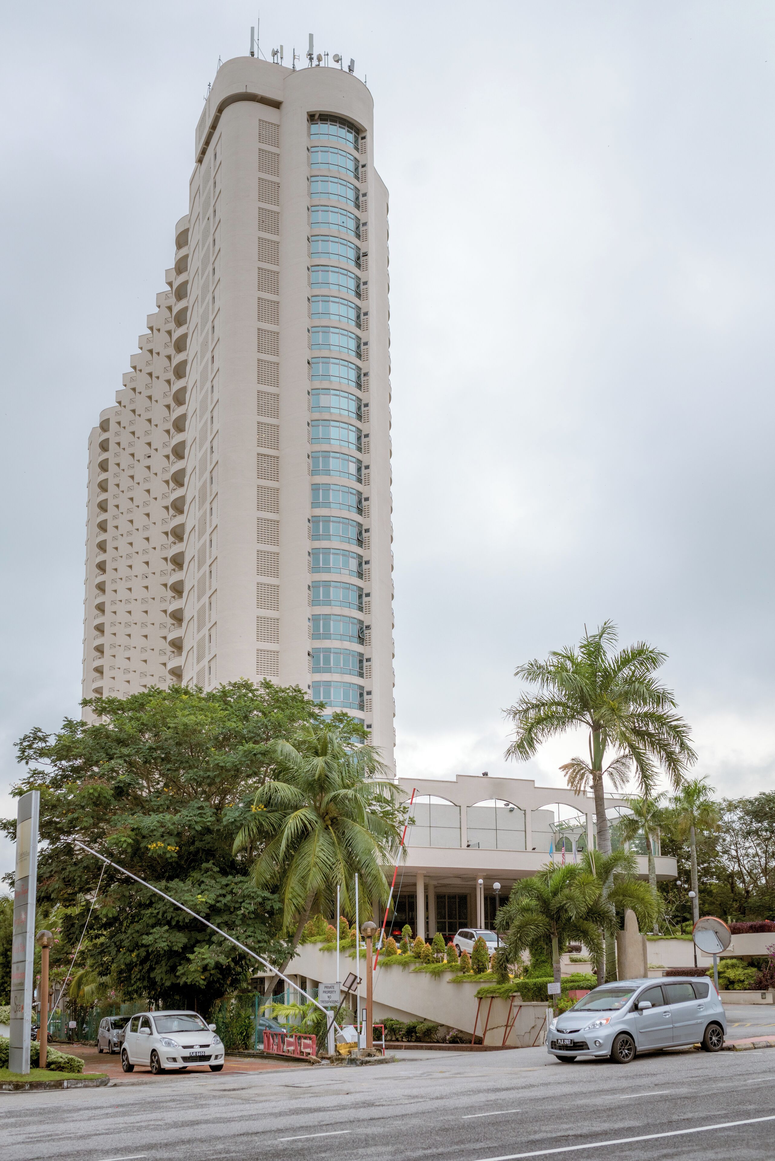 A tall, beige building with a curved facade and multiple balconies.