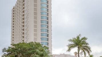 A tall, beige building with a curved facade and multiple balconies.