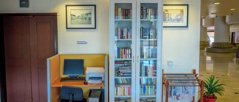 A library with bookshelves, a computer desk, and a printer.