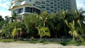 A tall, modern hotel with a curved facade and multiple balconies. - Rainbow Paradise Beach Resort by LWE (George Town)