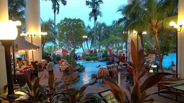 A resort pool area with palm trees, tables, and umbrellas. - Rainbow Paradise Beach Resort by LWE (George Town)