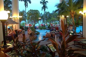 A resort pool area with palm trees, tables, and umbrellas. - Rainbow Paradise Beach Resort by LWE (George Town)