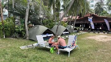 A campsite with tents and a dining area with tables and chairs.