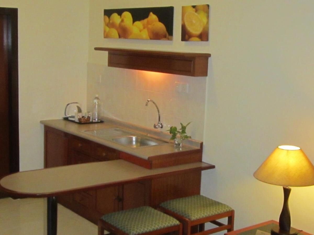 A compact kitchen with a sink, a small countertop, and a chair.