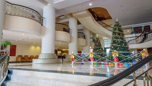 A spacious lobby with a grand staircase, multiple levels, and a Christmas tree. - Rainbow Paradise Beach Resort by LWE (George Town)