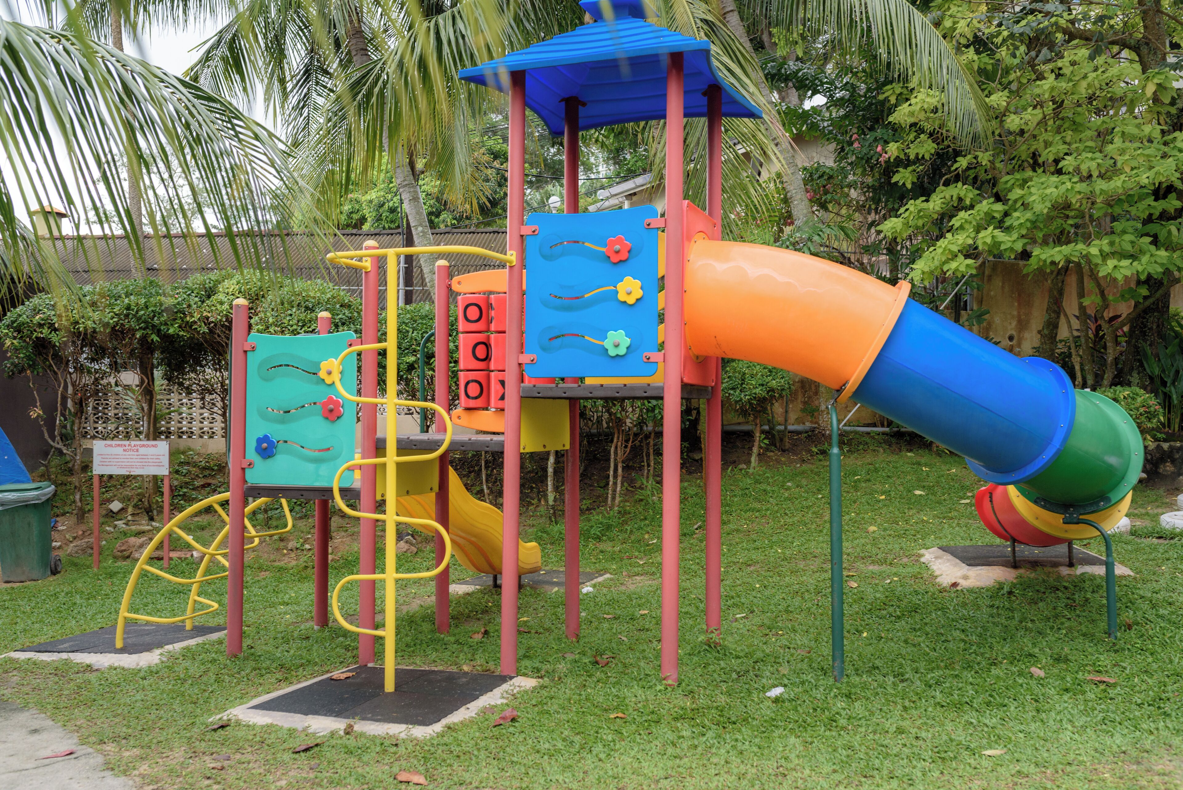 A playground with a slide, climbing structures, and a playhouse.