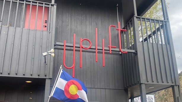 A building with a 'UPLIFT' sign, a Colorado flag, and red chairs outside. - King Room, Economy, Boutique Mtn Motel Idaho Springs (Idaho Springs)