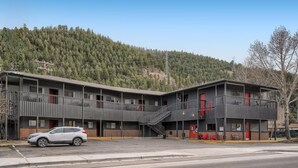 A motel with two-story buildings, a parking lot, and a mountainous backdrop. - King Room, Economy, Boutique Mtn Motel Idaho Springs (Idaho Springs)