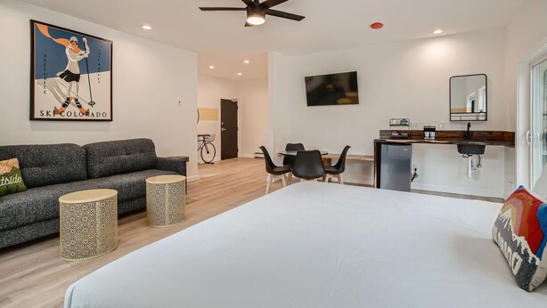 Een moderne hotelkamer met een groot bed, een bank, een eethoek en een kitchenette.