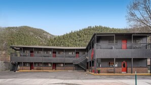 A two-story motel with a central staircase, red doors, and a parking lot in front. - King Room, A/C, Boutique Mtn Motel Idaho Springs (Idaho Springs)