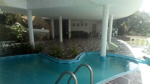 Piscina coperta con pavimento in pietra e zona relax con sedute.