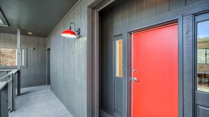 A hallway with a red door, a grey wall, and a red pendant light. - 2x King Room, A/C, Balcony, Mtn Boutique Motel (Idaho Springs)