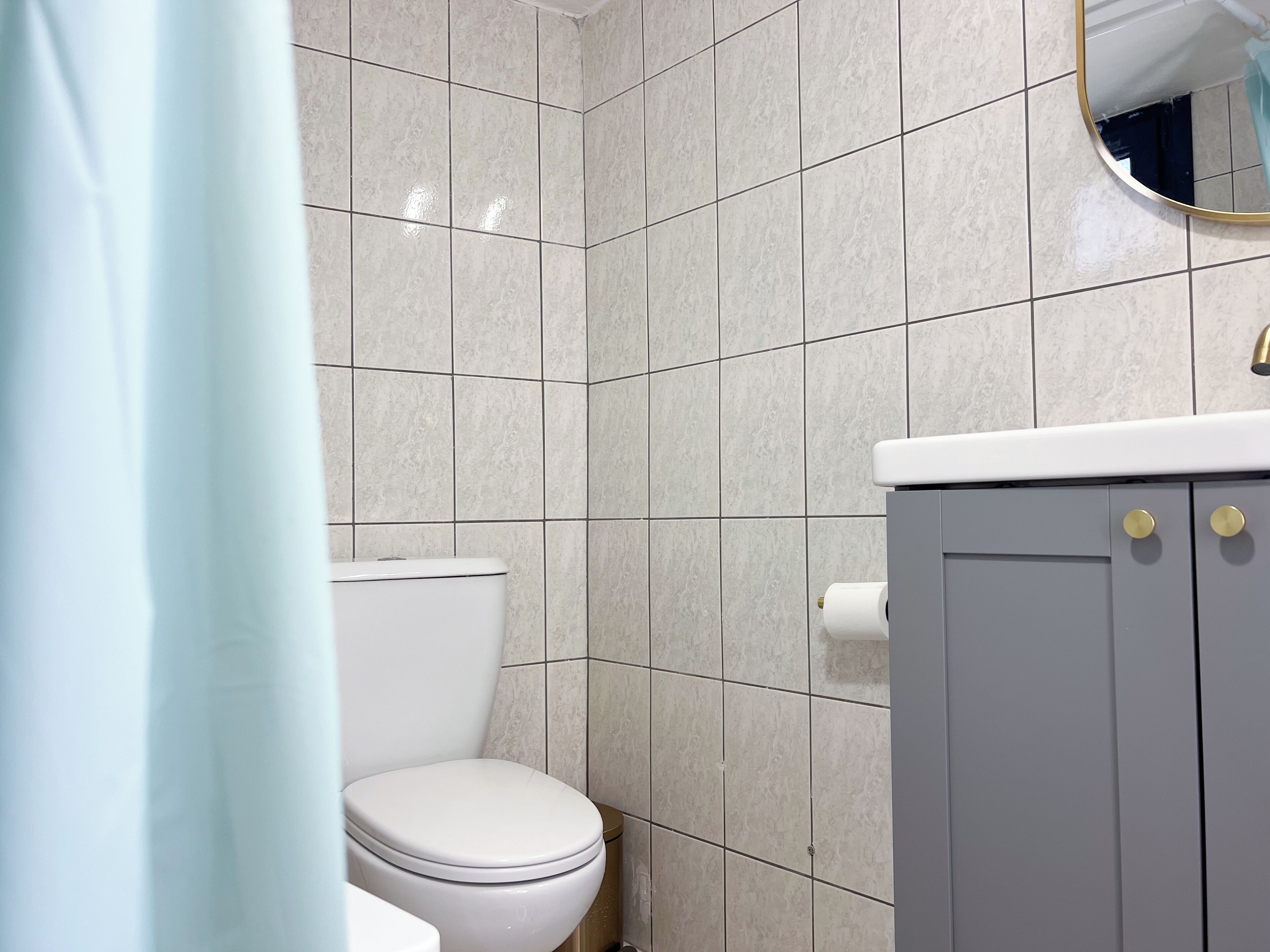 A bathroom with a toilet, a sink with a mirror, and tiled walls.