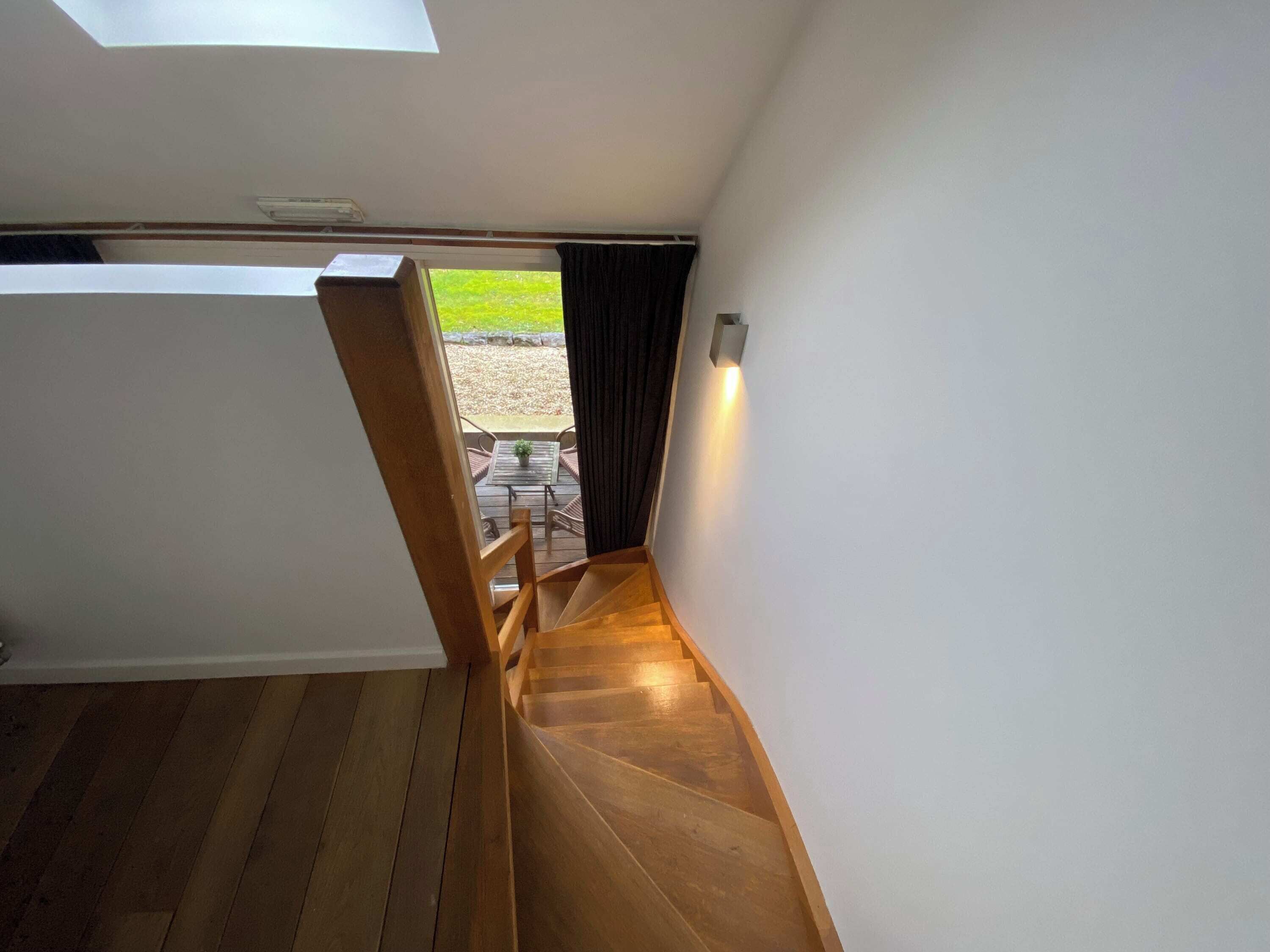 A wooden staircase leading to an outdoor area with a table and chairs.