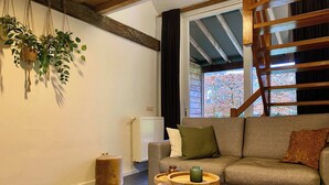 A cozy living room with a sofa, a small wooden side table, and hanging plants.