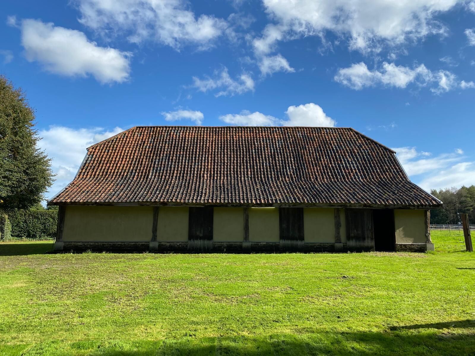 A single-story building with a tiled roof, surrounded by a grassy field.