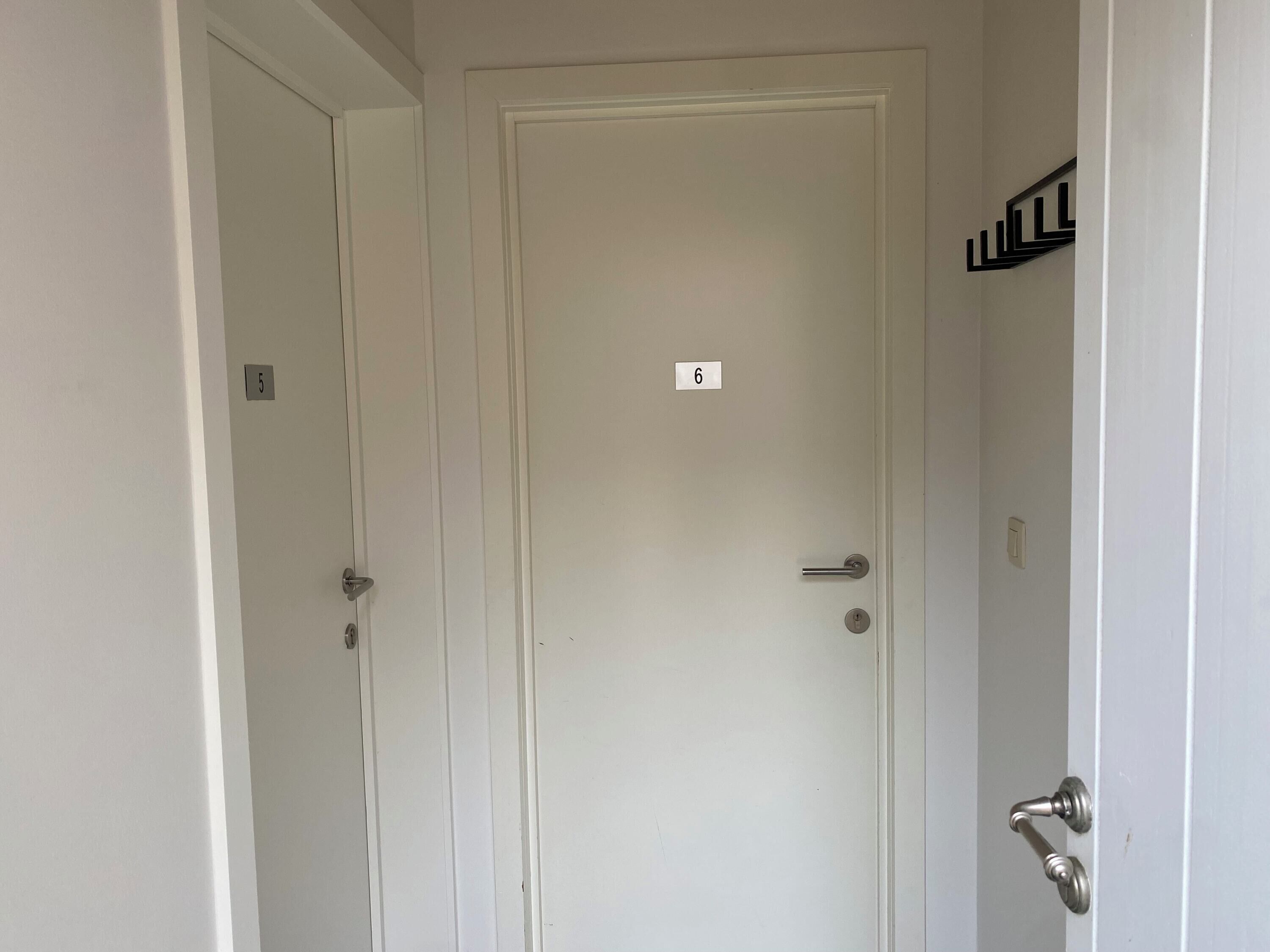 Una porta bianca con il numero 6, una maniglia e una serratura.