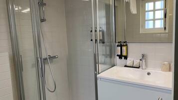 Un bagno moderno con doccia vetrata, lavandino bianco e specchio sopra il lavandino.