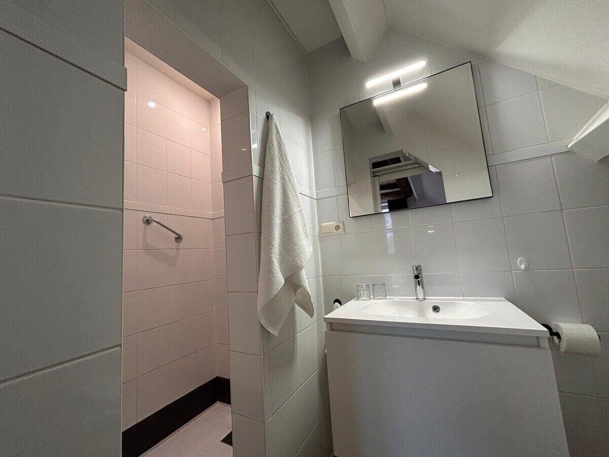 A modern bathroom with a shower, sink, and mirror.
