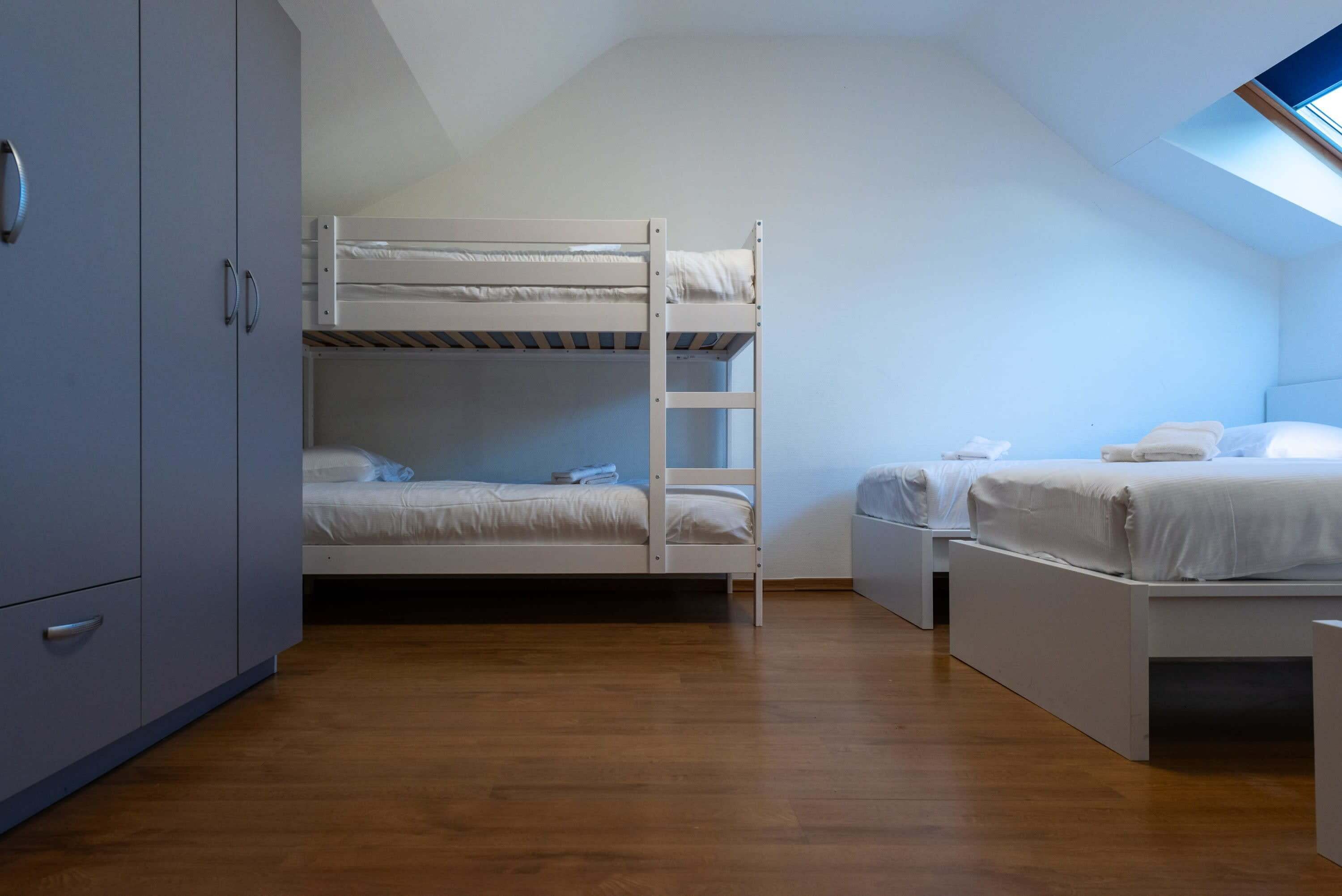 Une chambre avec un lit superposé, un bureau et une armoire.