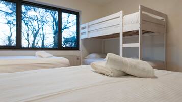 A room with bunk beds and a window with a view of trees.