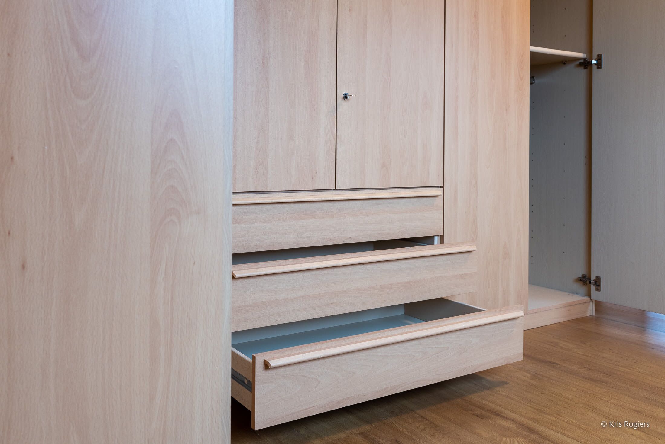 A wooden wardrobe with multiple drawers and a door.
