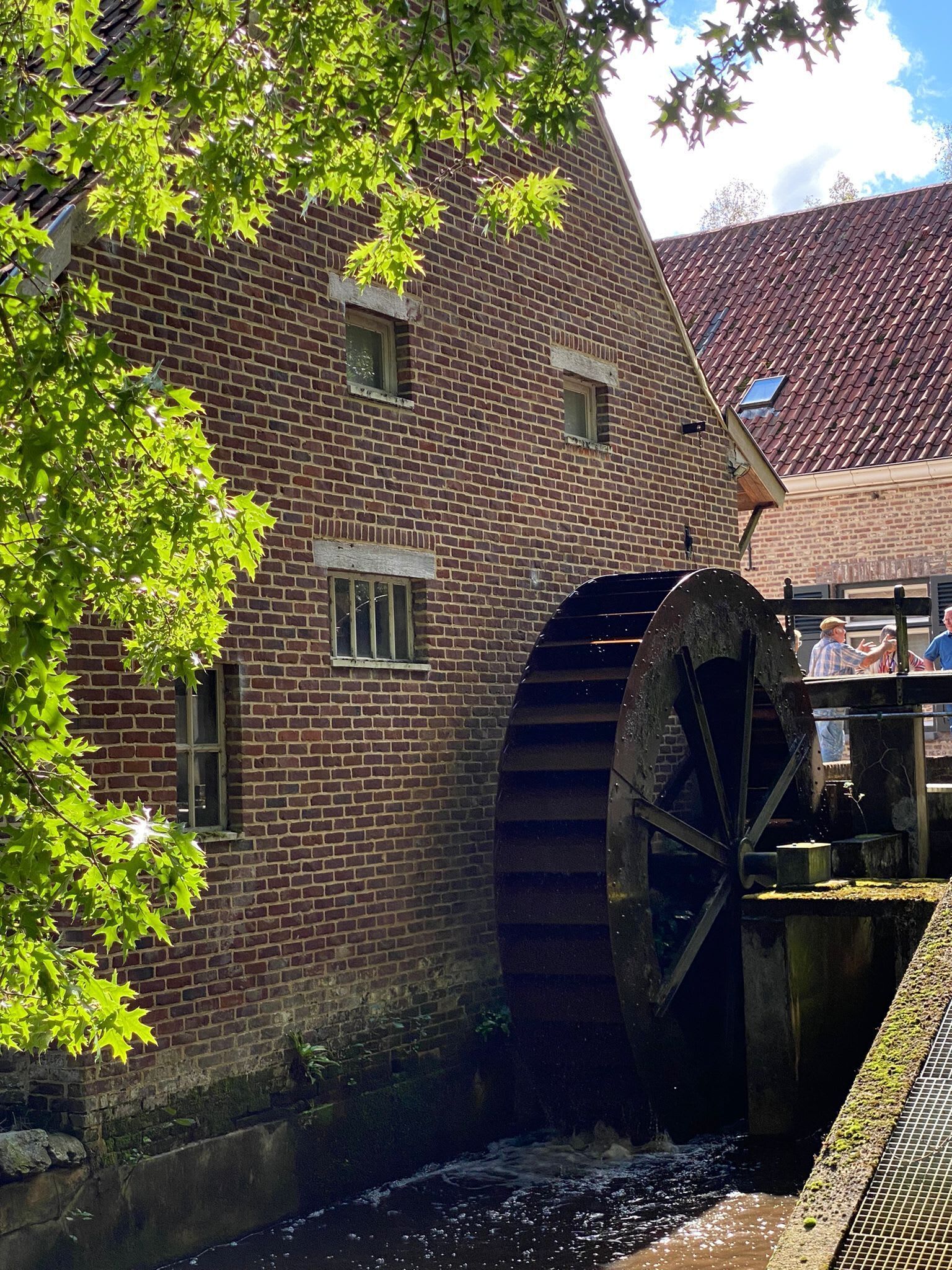 Un bâtiment en briques doté d’une grande roue à eau et bordé d’un canal.