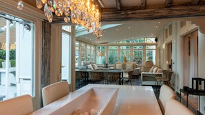 A spacious room with a large dining table, comfortable seating, and a chandelier.