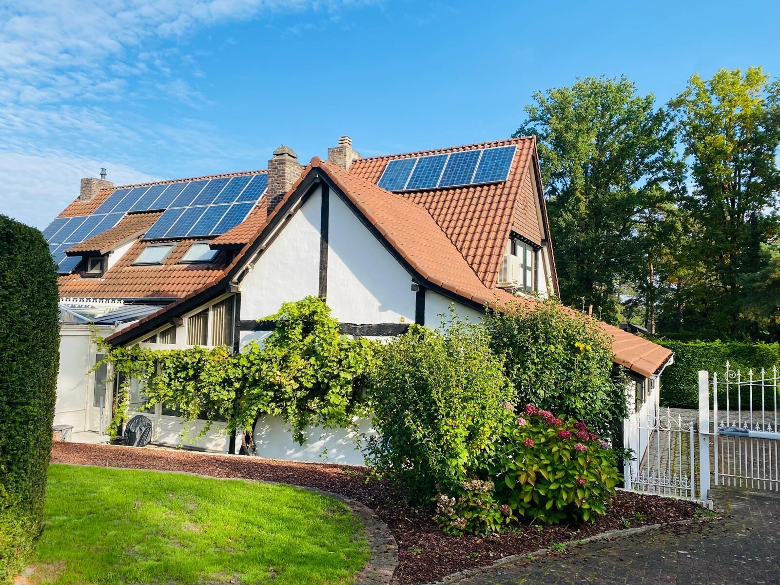 A traditional house with a sloped roof, solar panels, and a well-maintained garden.