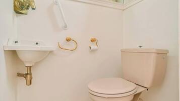 Un bagno con un lavandino bianco, un water e un rubinetto dorato.